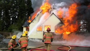 House on fire with firemen putting it out